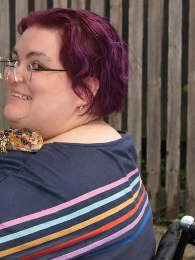 Participant smiling outdoors while holding a pet lizard